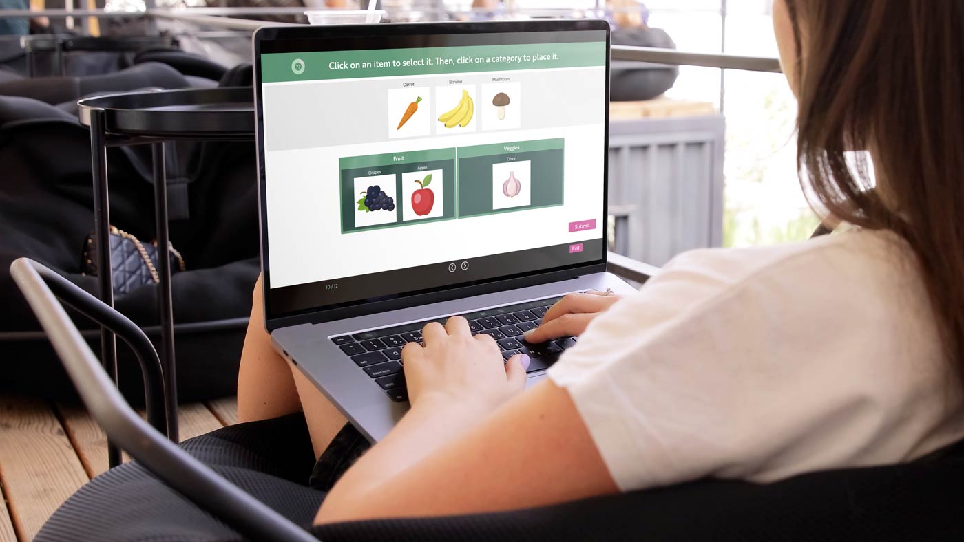 A laptop showing the REACHUM Tap Tap activity, with items being sorted into two labelled category columns